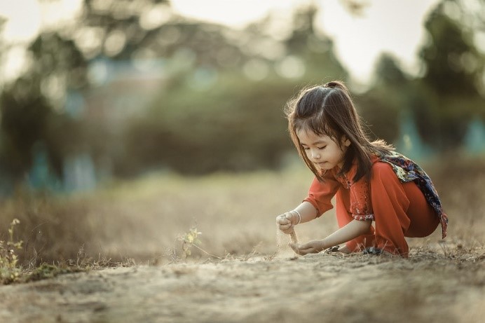Young girl squatting down picking soil